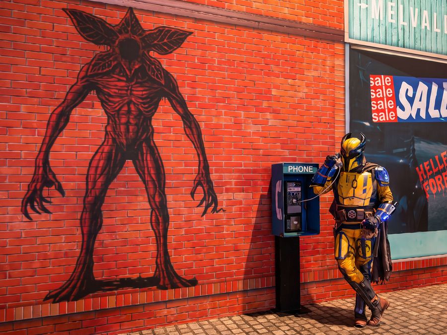 Cosplayer in gelb-blauer Rüstung vor einer inszenierten Stadtkulisse auf der gamescom