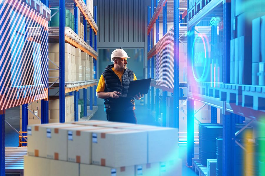Digitale Lagerlogistik und Automatisierung Mitarbeiter mit Laptop in einem Lager vor Regalen und digitalen Datenanzeigen